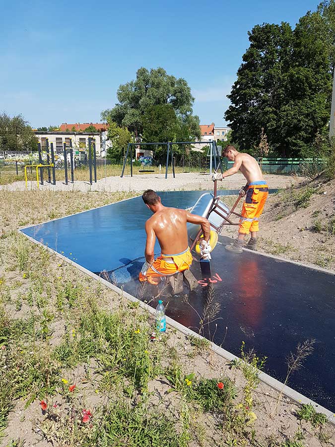 Arbeiter bringen blauen Asphalt auf